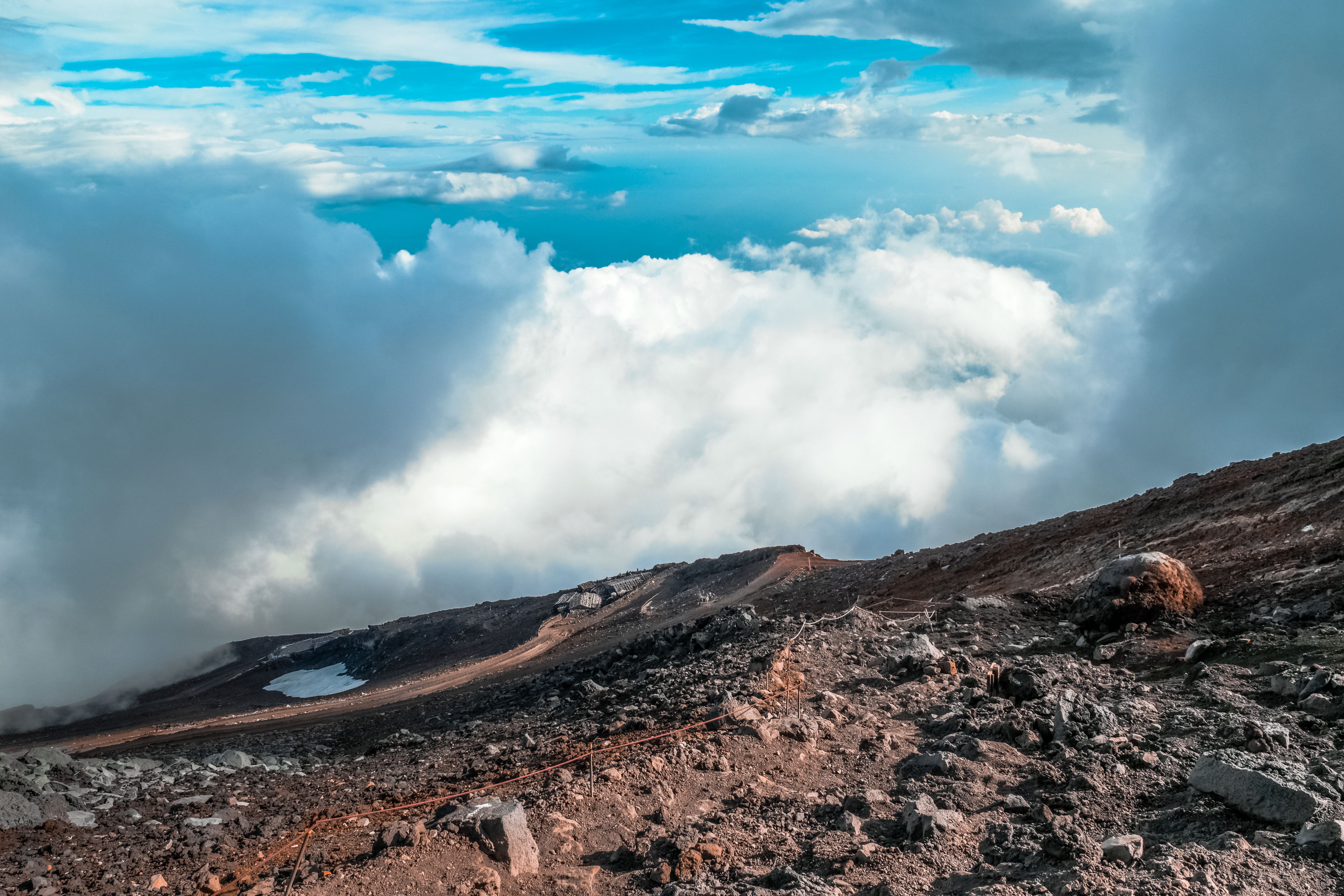 Stunning landscape from Mount Fuji summit, showcasing clouds and rugged terrain.