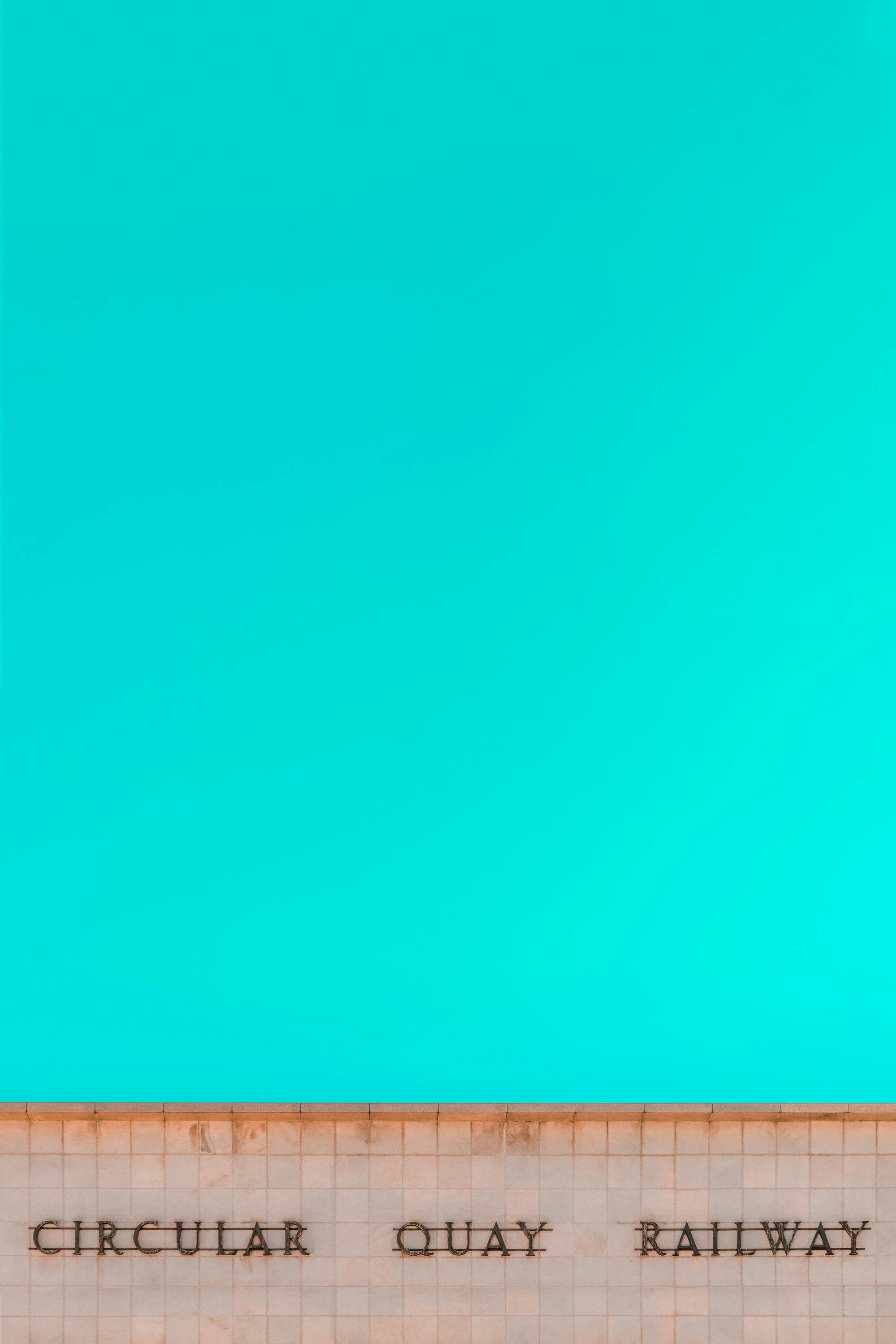 Minimalist composition of Circular Quay Railway sign with cyan sky in Sydney, Australia.