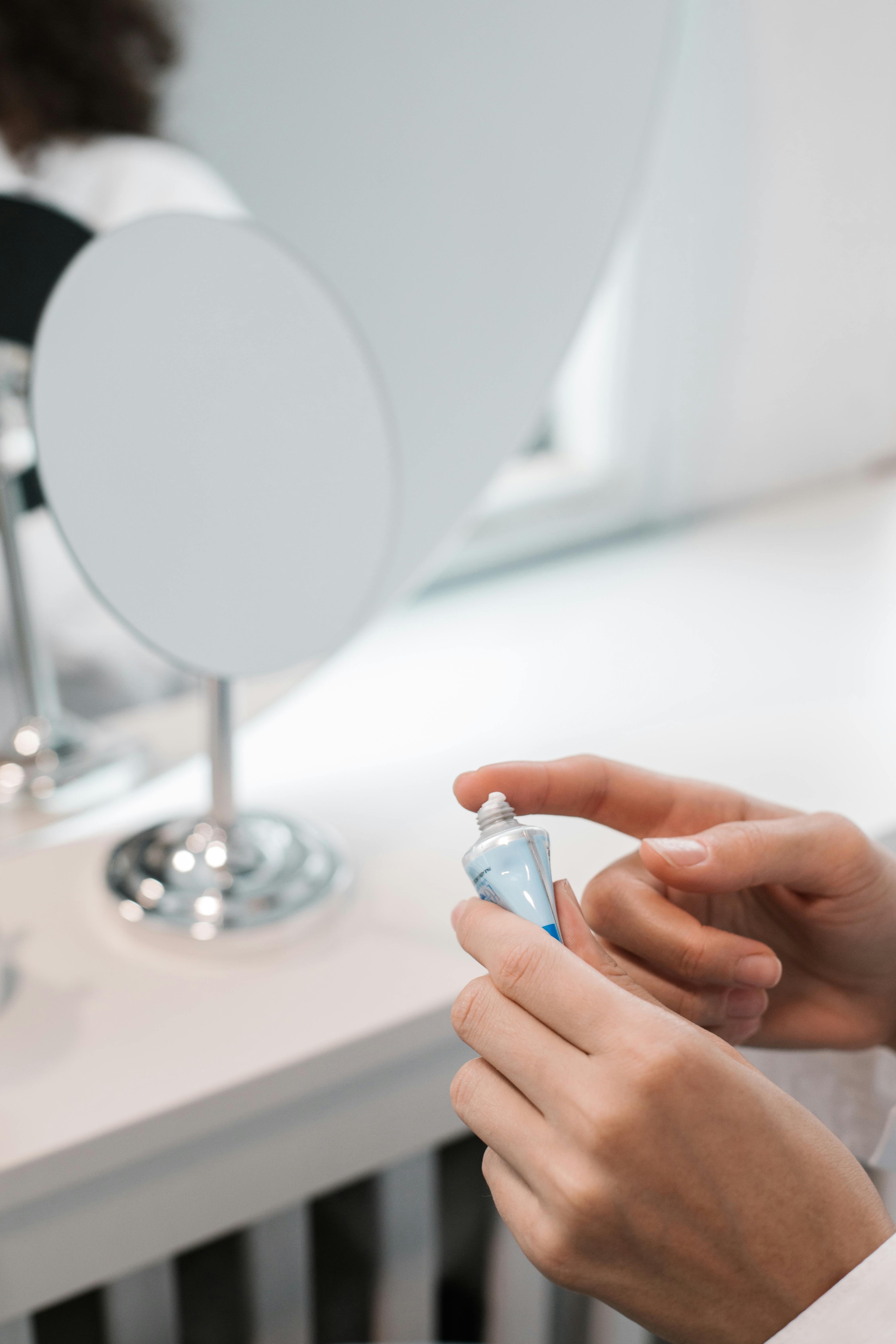 Hands applying skincare cream in a minimalist setting for daily self-care routine.
