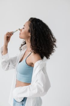A woman using a jade roller in a bright, minimal space for her skincare routine.