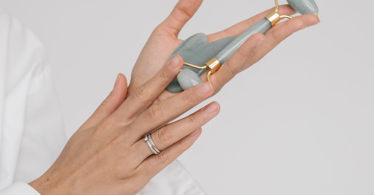 A person sitting cross-legged on a yoga mat, with their eyes closed, massaging their shoulders and neck with their hands.