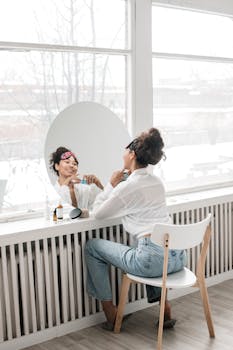 Woman applying skincare products in a bright room during her morning routine.