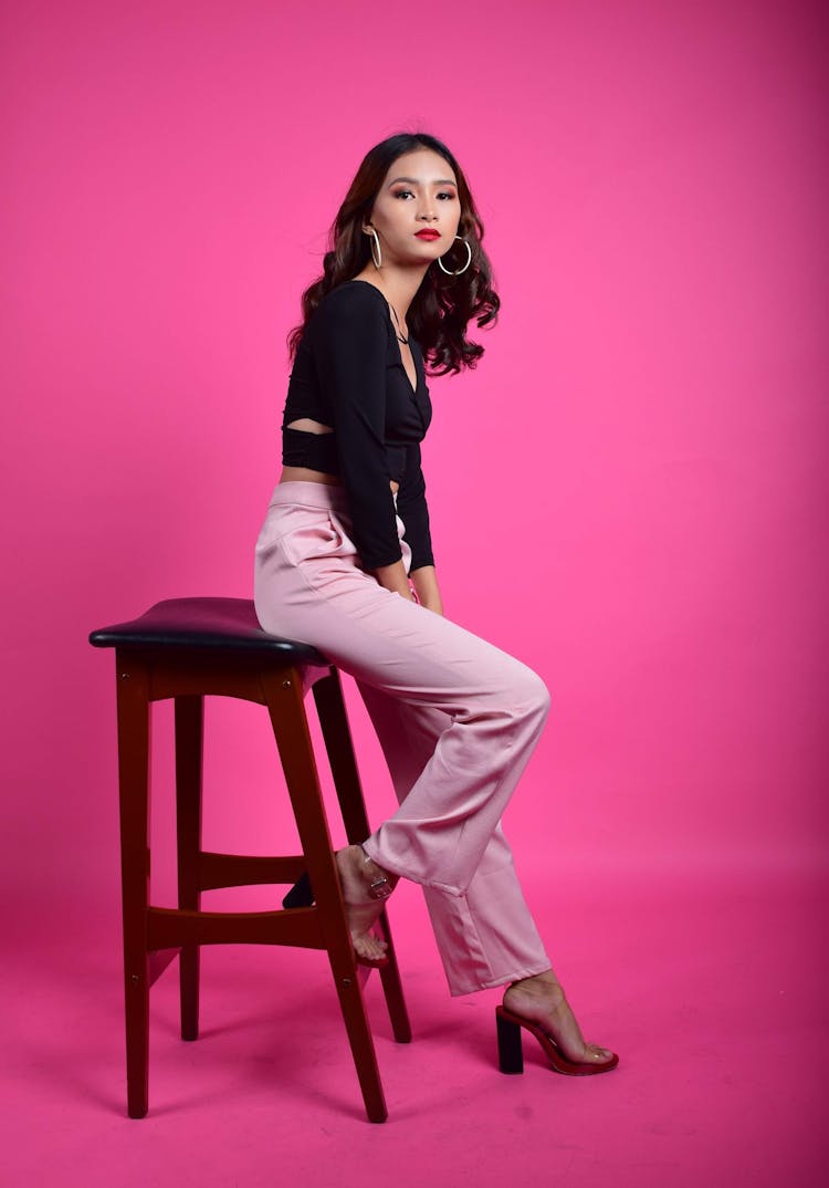 Curly Hair Woman In Pink Pants Sitting On Chair 