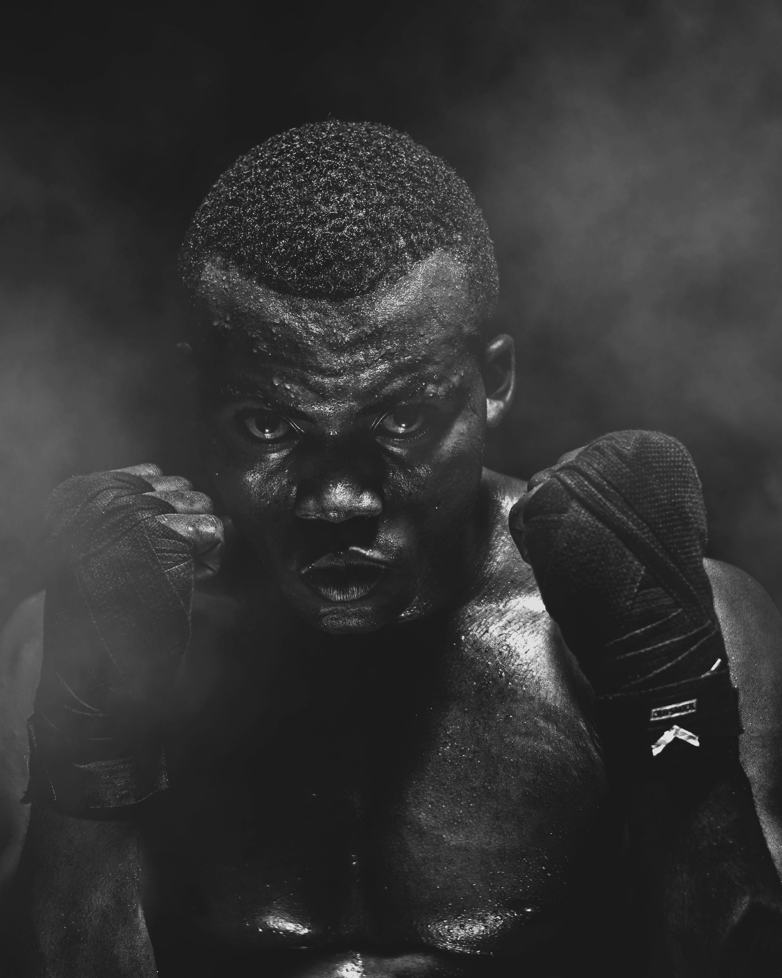 Dynamic black and white portrait of an athlete preparing for a boxing match, exuding strength and determination.