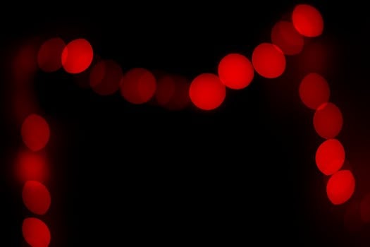 Red bokeh lights on a black background create an abstract and illuminated design.