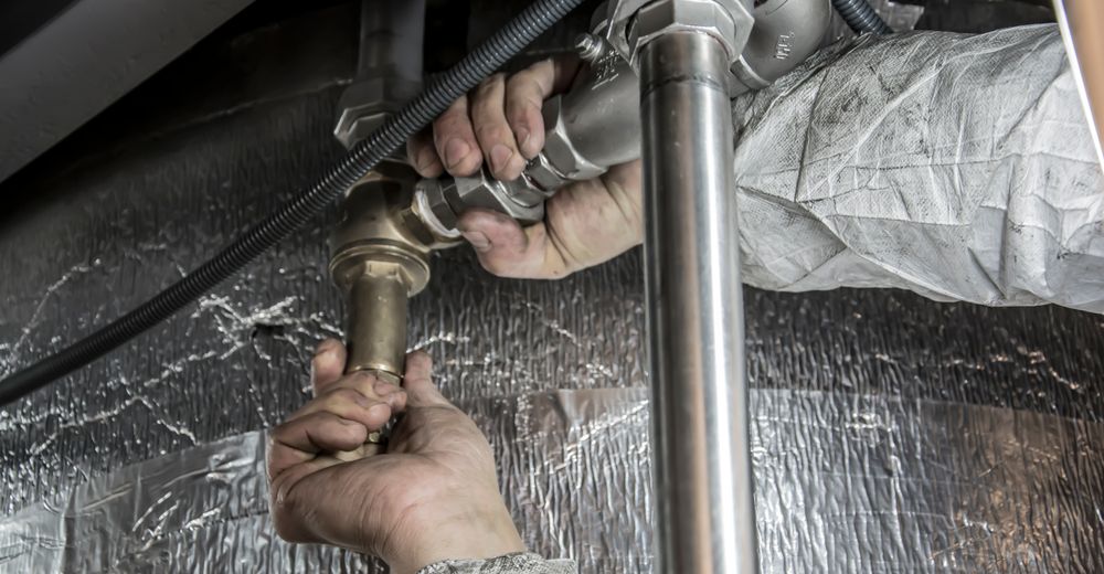Close-up of a technician tightening chrome pipes with a wrench