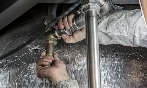 Plumber โ Close-up of a plumber's hands installing steel pipes indoors, showcasing skilled manual work.