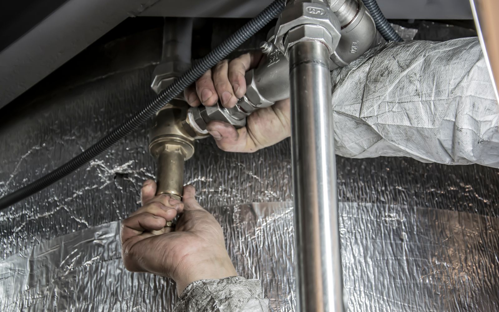 Hands fitting a threaded pipe connection with a wrench