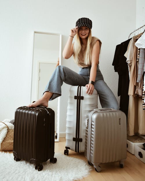 Free Woman in Jeans Sitting on Luggage  Stock Photo