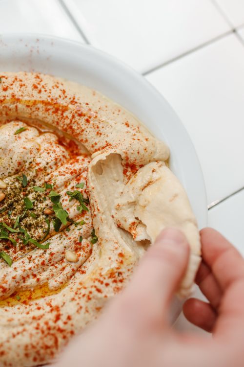 Free Delicious hummus topped with herbs and paprika served with pita bread, perfect for authentic cuisine enthusiasts. Stock Photo