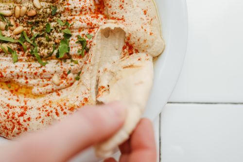 Free Delicious hummus with spices and a piece of pita bread being dipped, perfect for food lovers. Stock Photo