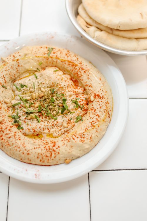 Free Close-up of creamy hummus garnished with spices and herbs, served with pita bread. Stock Photo