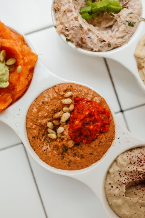 Free Close-up of assorted flavorful dips in sleek ceramic bowls on a tiled tabletop. Stock Photo