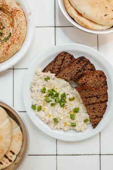 A delicious gourmet dip with sliced bread presented on a white tiled surface, perfect for culinary inspiration.