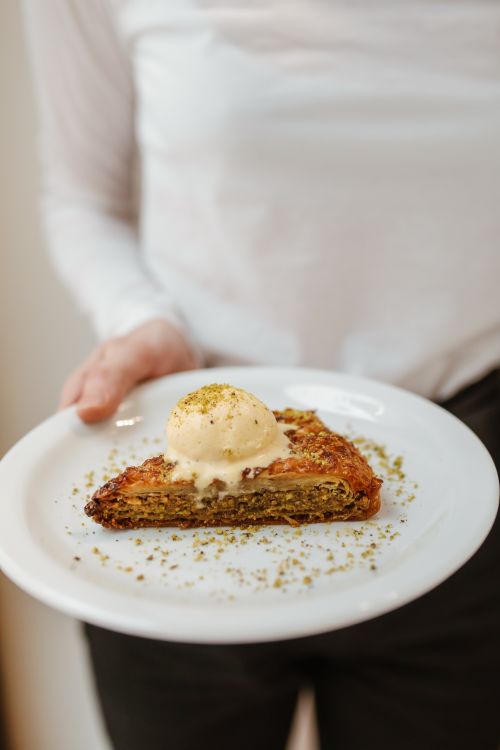 Free A tempting slice of baklava topped with ice cream, garnished with pistachios, perfect for dessert lovers. Stock Photo