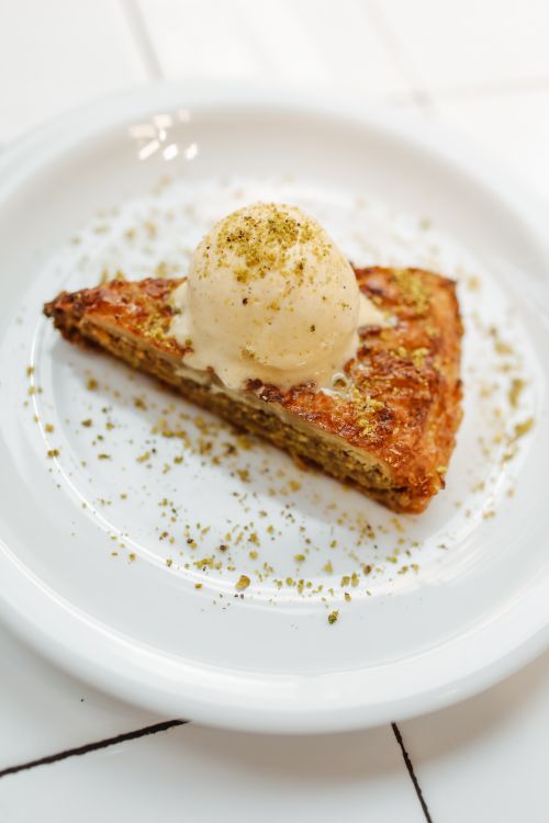 Free Close-up of baklava slice topped with scoop of ice cream on a white plate. Stock Photo