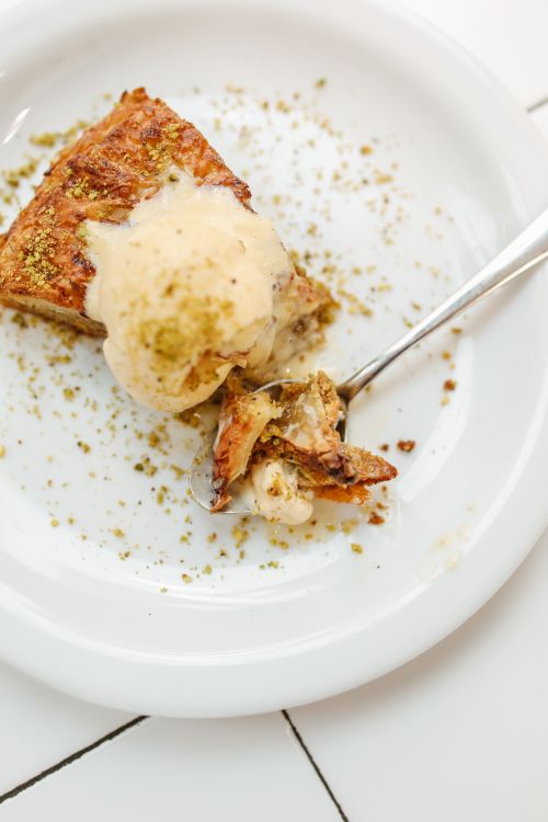 Free Close-up of baklava dessert topped with ice cream and pistachios on a white plate. Stock Photo