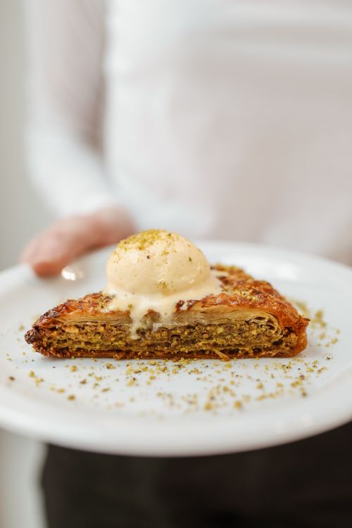 Free A delectable slice of baklava topped with ice cream, served on a ceramic plate. Stock Photo