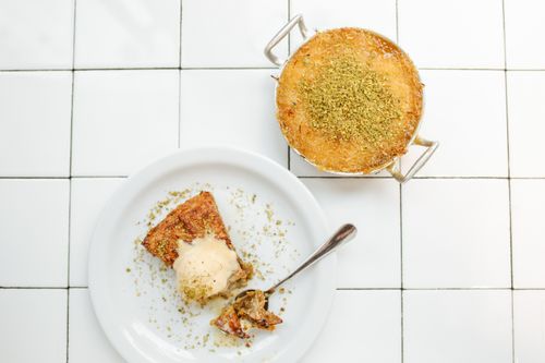 Free A delectable slice of knafeh with ice cream on a tile background, showcasing its rich texture and flavor. Stock Photo