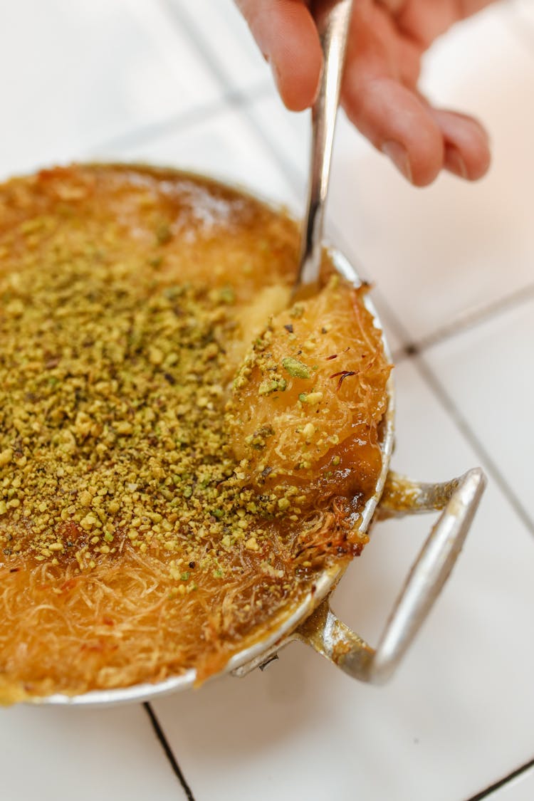 A Person Getting Knafeh With A Spoon