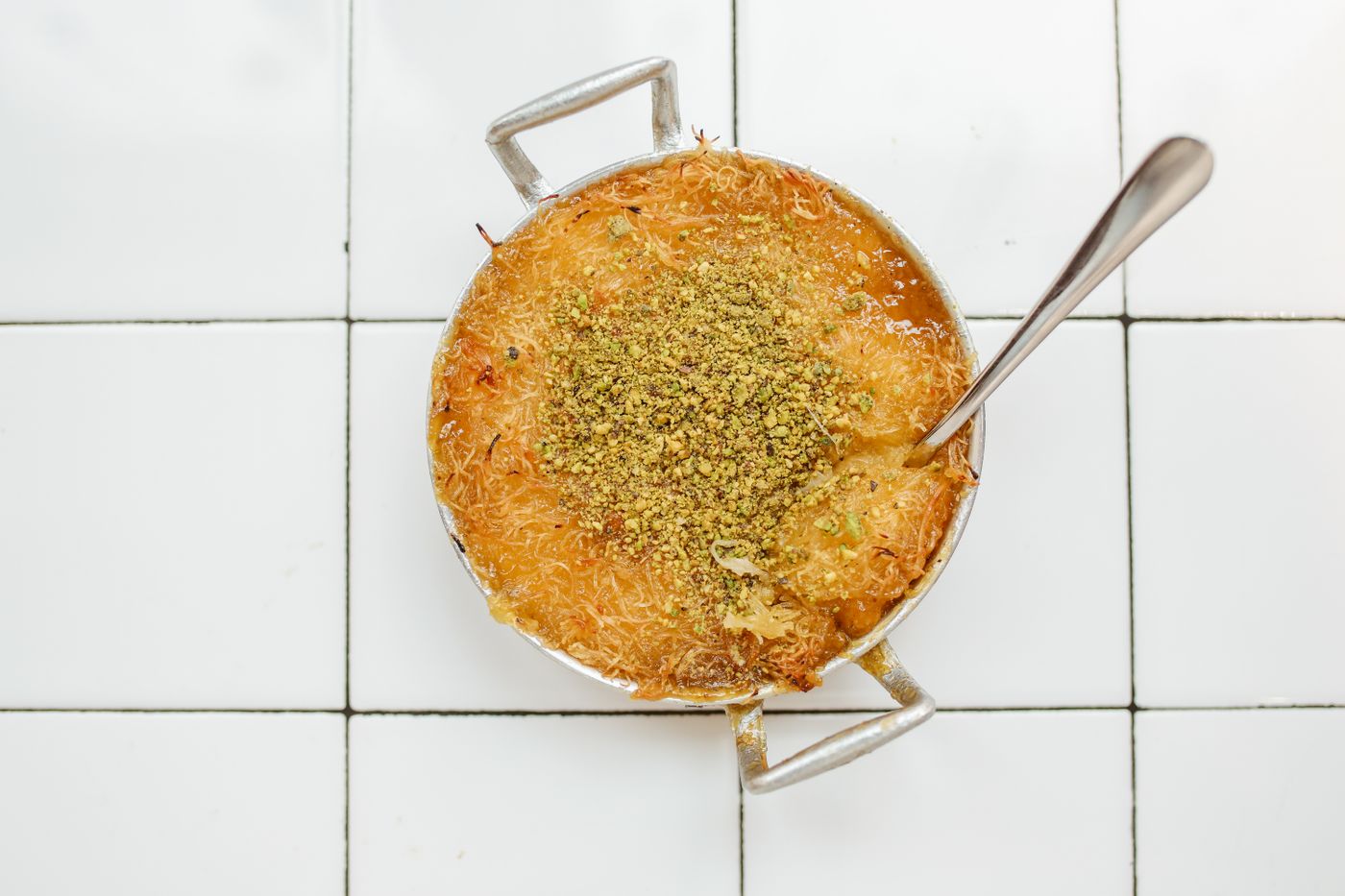Savor a close-up view of traditional knafeh topped with crushed pistachios, capturing a taste of Middle Eastern cuisine.