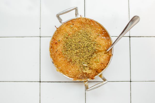 Savor a close-up view of traditional knafeh topped with crushed pistachios, capturing a taste of Middle Eastern cuisine.