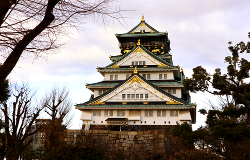 Free Majestic view of Osaka Castle surrounded by bare trees under a cloudy sky during winter. Stock Photo