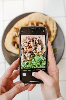 Hands taking a photo of a taco with a smartphone, showcasing food styling and photography skills.