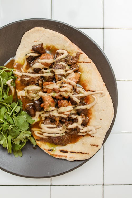 Pita Bread With Pork and Sauce on Black Plate