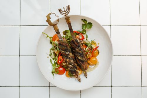 Free Grilled kebabs served on a fresh salad with vibrant vegetables, perfect for a gourmet meal. Stock Photo