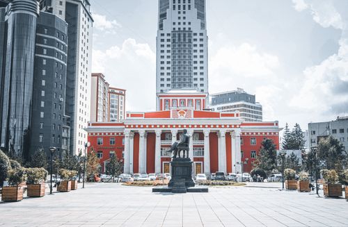 Free Distinctive red building with grand columns and statue in urban setting. Stock Photo