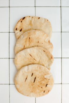 Close-up of homemade pita bread on a tiled ceramic surface, showcasing traditional baking.