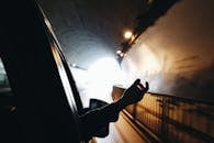 开车穿过灯光明亮的隧道时，一只手从车窗伸出