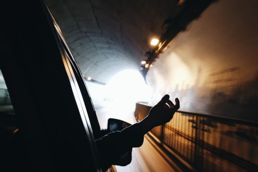 开车穿过灯光明亮的隧道时，一只手从车窗伸出
