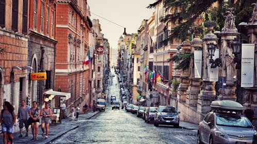 Free Busy urban street in Rome with people, cars, and historic architecture showcasing Italian urban lifestyle. Stock Photo