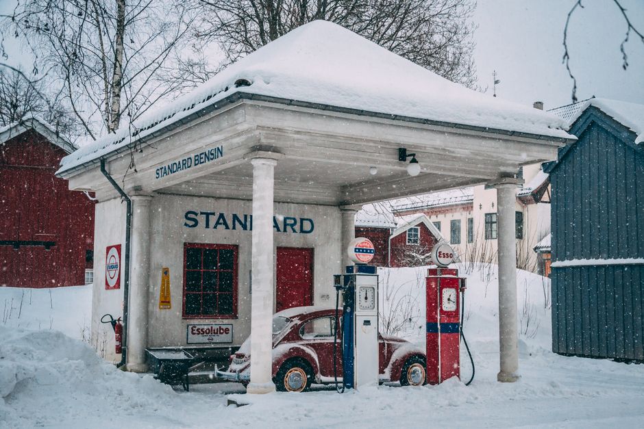 A vintage gas station covered in snow during a winter day