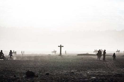 Silhouetted people and horses in the misty sands of Bromo, East Java at sunrise.