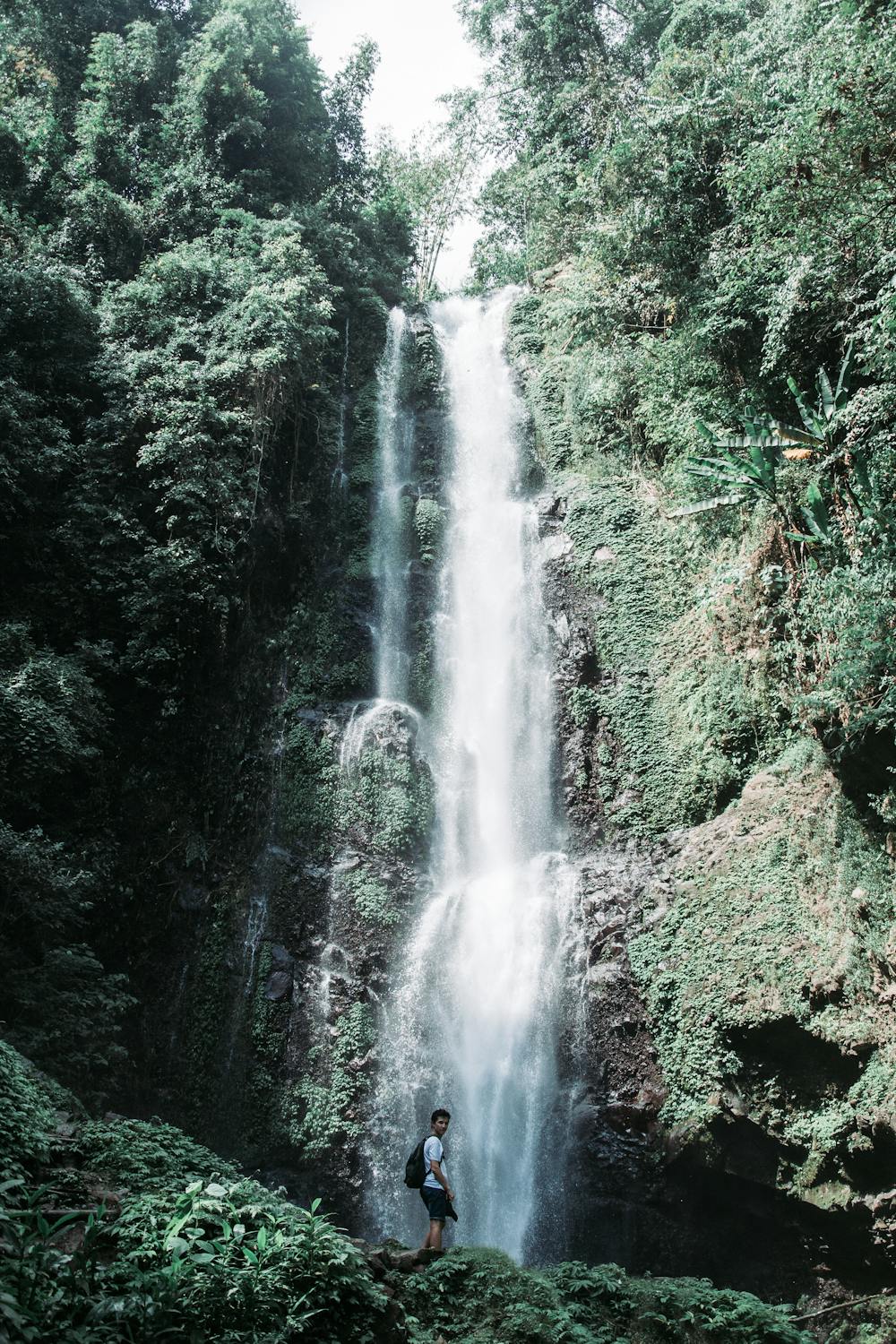 Natural swimming pool with clear blue water beneath waterfall