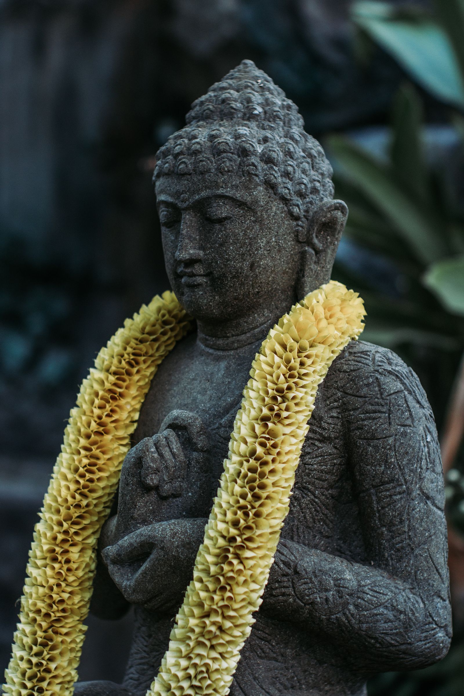 Stone statue with frangipani garland