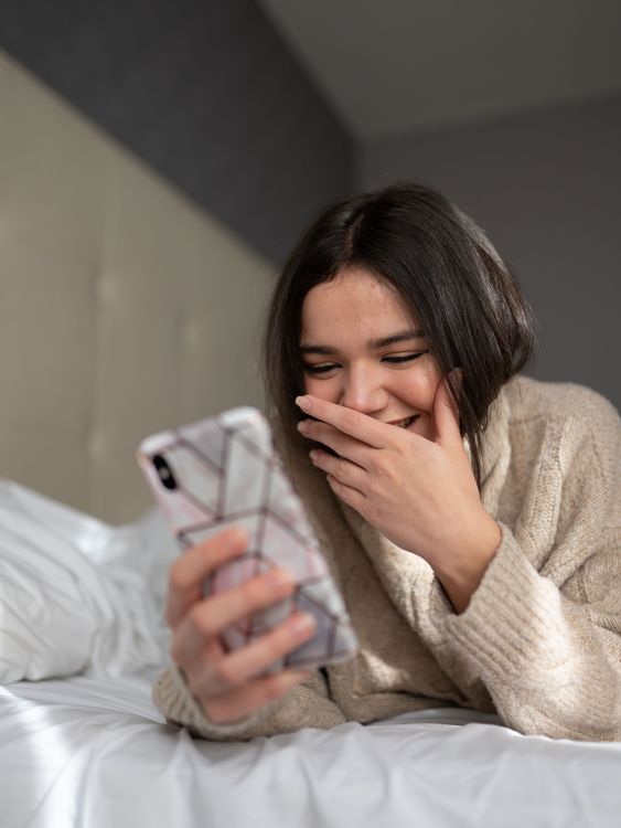 Smiling woman messaging on her smartphone while relaxing at home