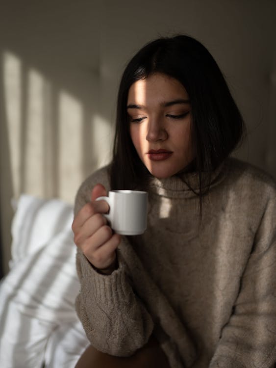 Dreamy young woman drinking coffee on bed · Free Stock Photo
