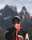 Serious young male hiker standing near snowy mountains in sunlight