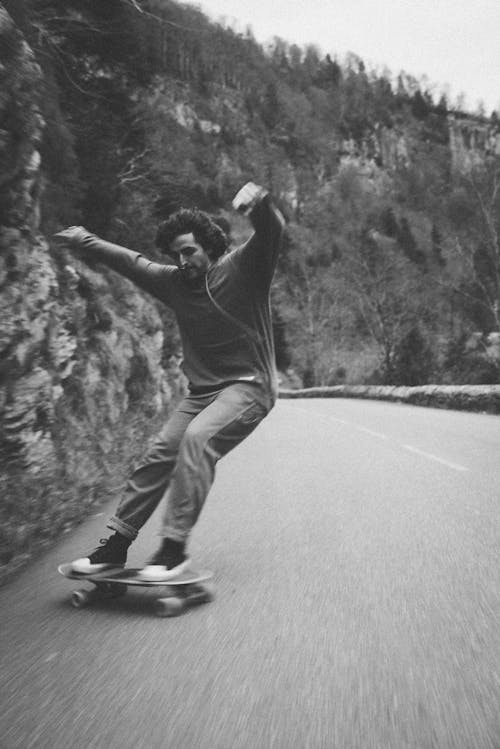 Energetic young guy riding skateboard on road