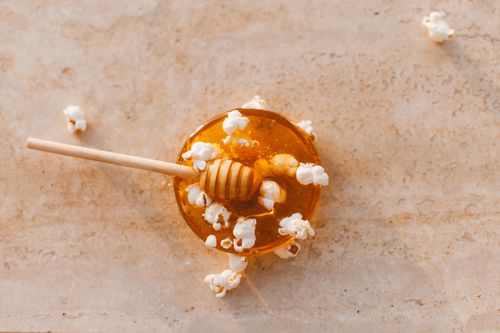Free Top view of honey drizzler with popcorn on marble, perfect culinary texture. Stock Photo