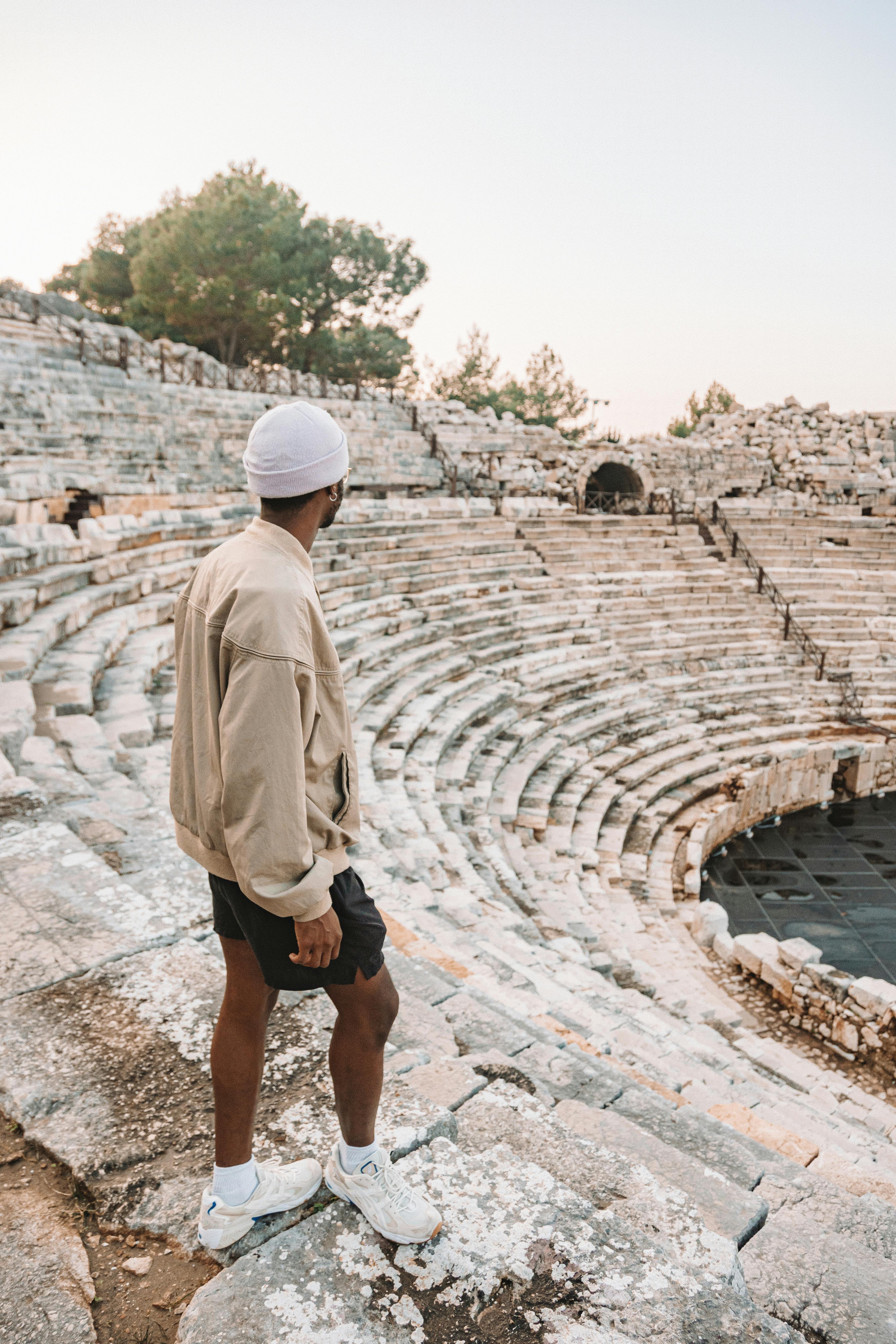 Free Man exploring an ancient stone amphitheater, capturing the essence of historic travel and adventure. Stock Photo