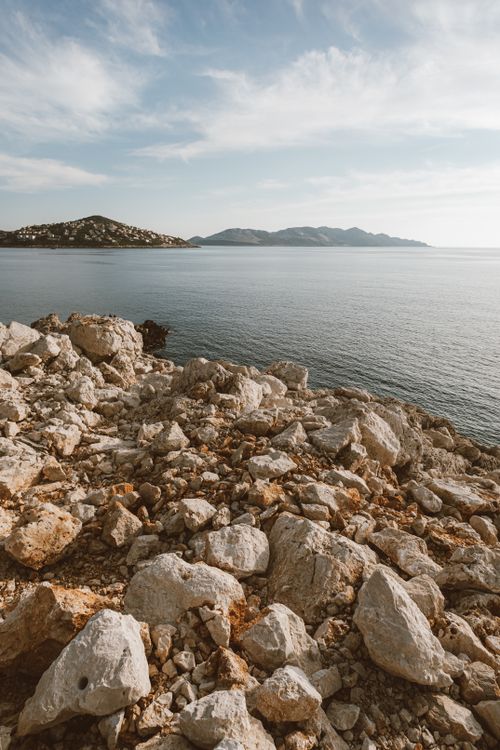 Free Expansive rocky shoreline overlooking serene blue waters and distant islands. Stock Photo