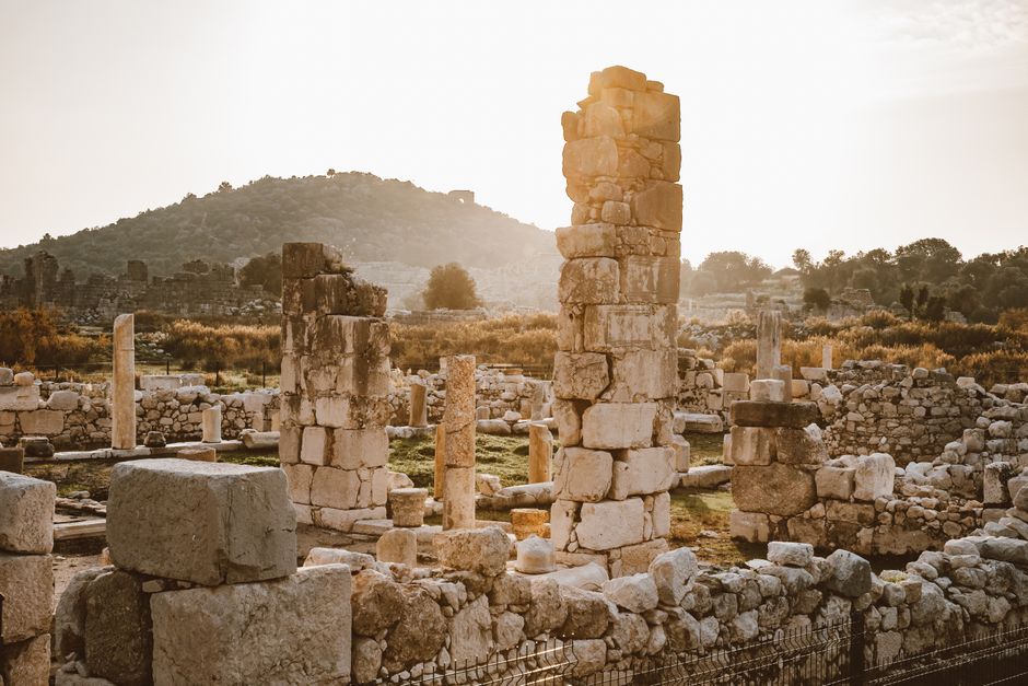 Explore the serene beauty of ancient ruins with towering columns at sunset, evoking history and tranquility.