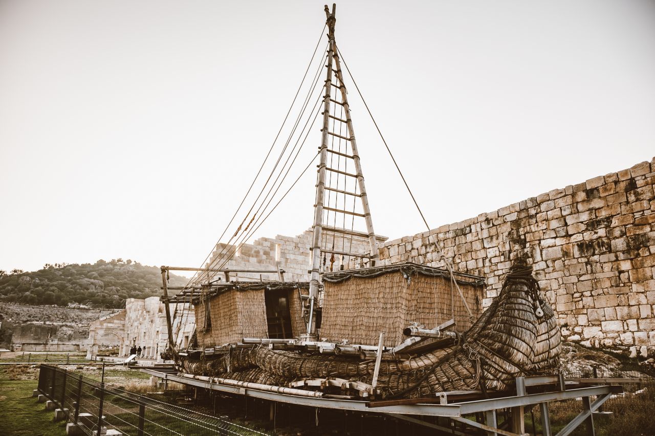 antique ship replica displayed near ancient stone walls in sunset ligh