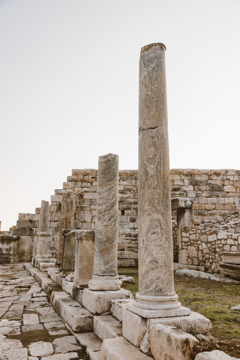 Explore the ancient ruins of Dougga, showcasing historic architecture and stone columns in Tunisia.