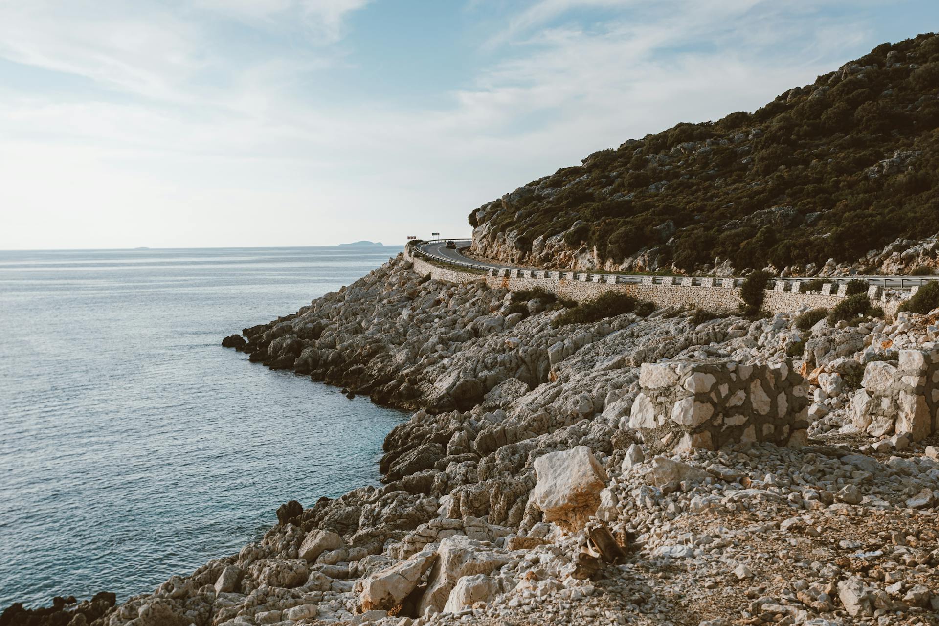 Discover a stunning coastal road that winds alongside a rocky shoreline and serene ocean views.